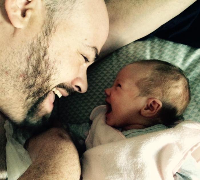 Father laying with baby, both laughing